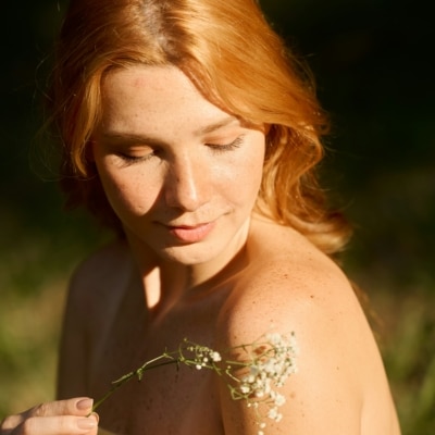 Jeune femme en extérieur portant une fleurs dans la main