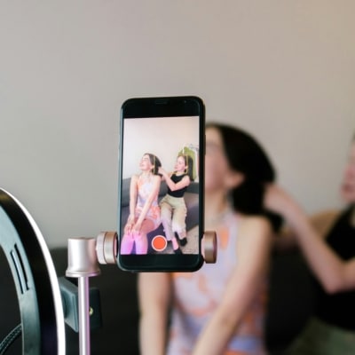 Deux femmes se filmant avec un smartphone pendant que l'une coiffe l'autre
