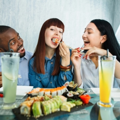 Un homme et deux femmes mangeant des sushis