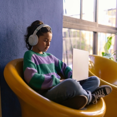 Une enfant assise avec un casque regardant un ordinateur