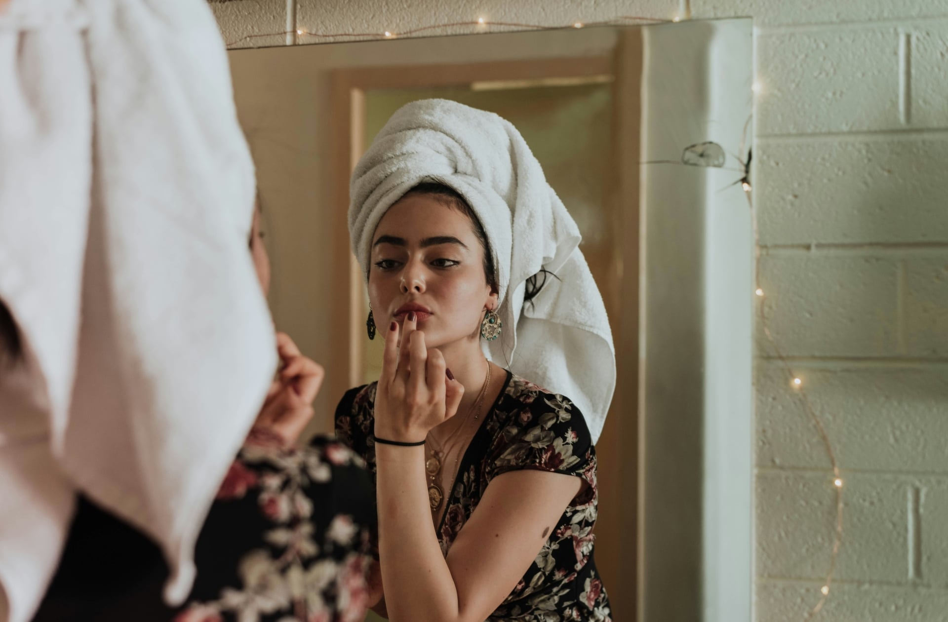 Femme qui se maquille et se prépare devant le miroir dans sa salle de bain
