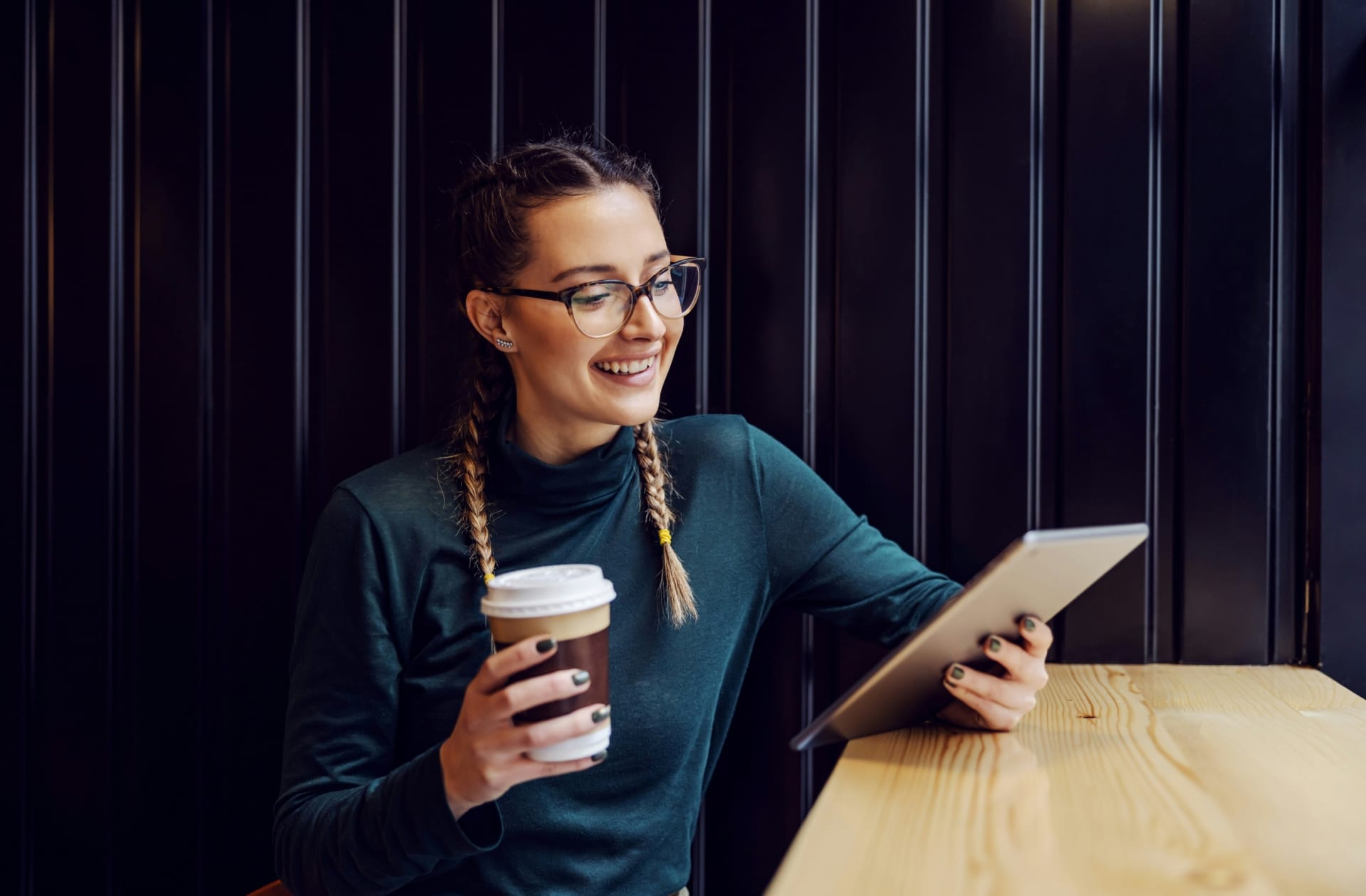 personne regardant une tablette un café à la main