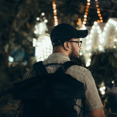 Homme portant une casquette, des lunettes et un sac à dos regardant des lumières