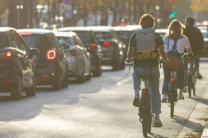 3 personnes de dos en vélo sur la route à coté de voiture en embouteillage
